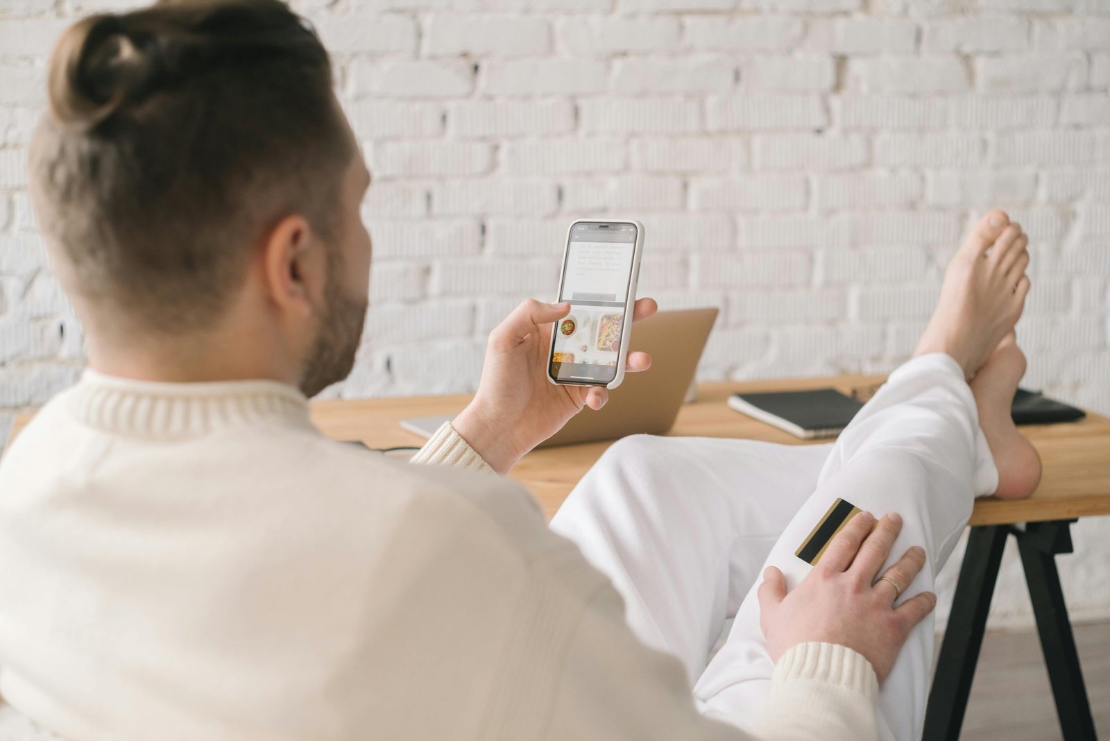 Relaxed man shopping online using smartphone and credit card